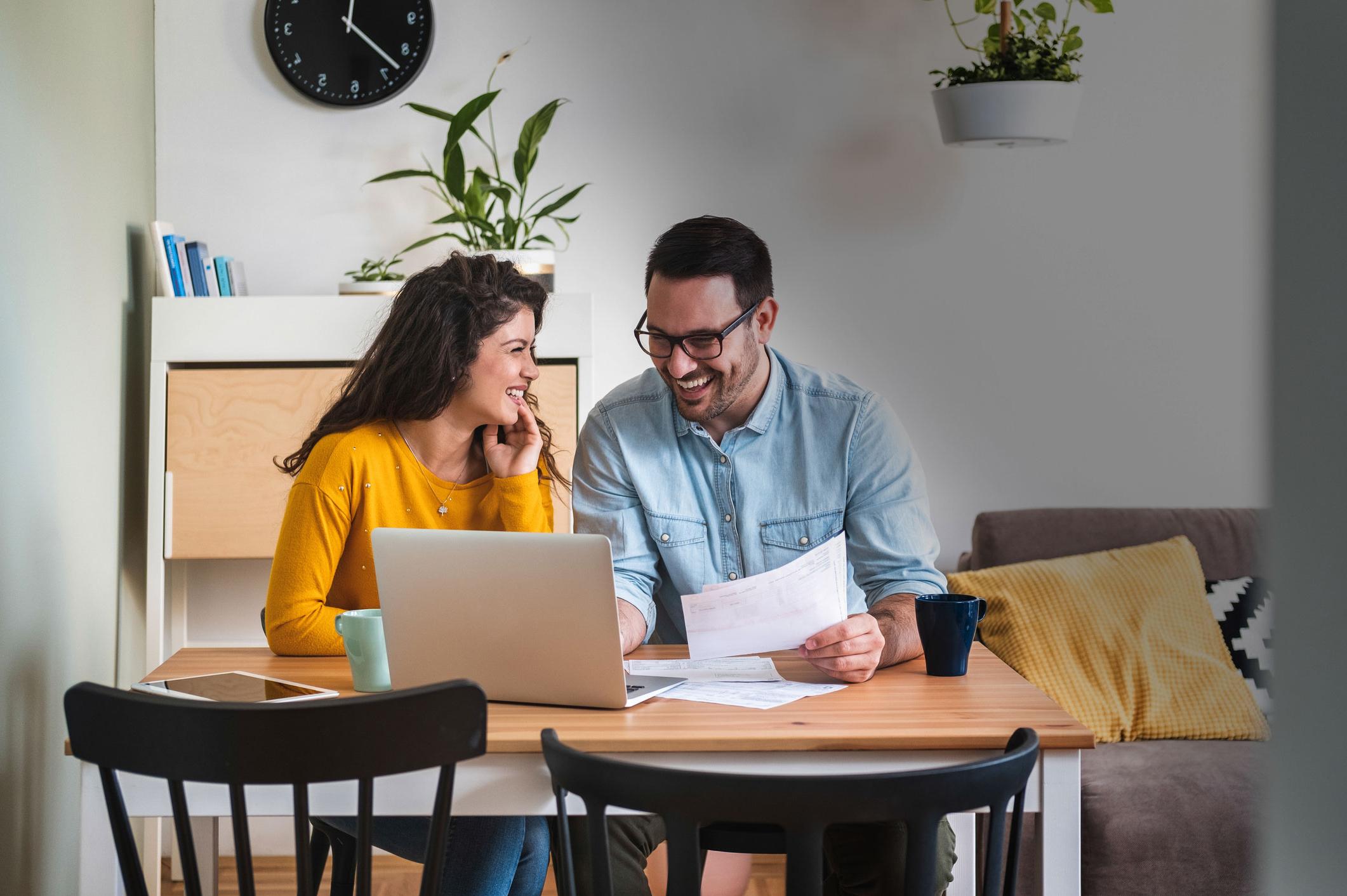 A couple paying bills at the dining room table